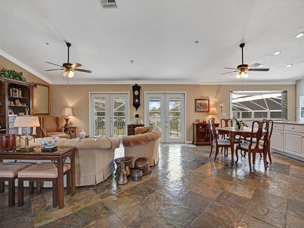 A spacious living and dining area features tile floors, two ceiling fans, and glass doors — 16270 FOREST MIST COURT, ALVA, FL