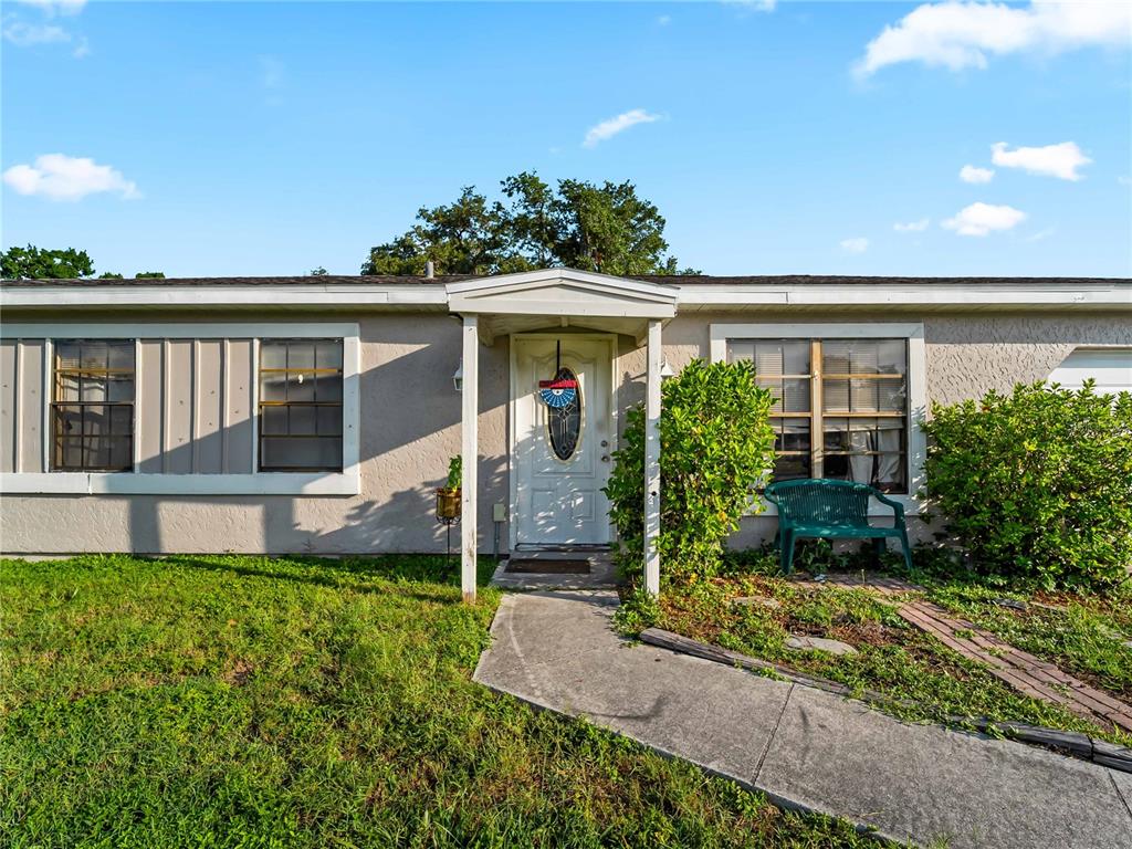 A single-story house with a white front door, a concrete walkway, and a green bench — 1018 RED BAY TERRACE NW, PORT CHARLOTTE, FL