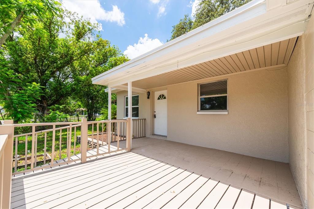 A covered porch with light-colored decking and railings leads to a white front door — 1808 S CLUB COURT, TAMPA, FL