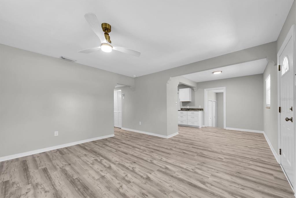 An empty living room features light gray walls, wood-look flooring, and a ceiling fan — 1808 S CLUB COURT, TAMPA, FL
