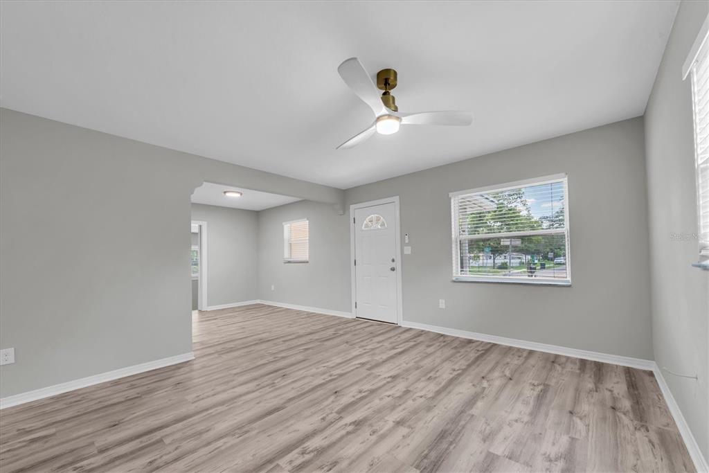 A living room with light gray walls, wood-look flooring, a ceiling fan, and a front door — 1808 S CLUB COURT, TAMPA, FL