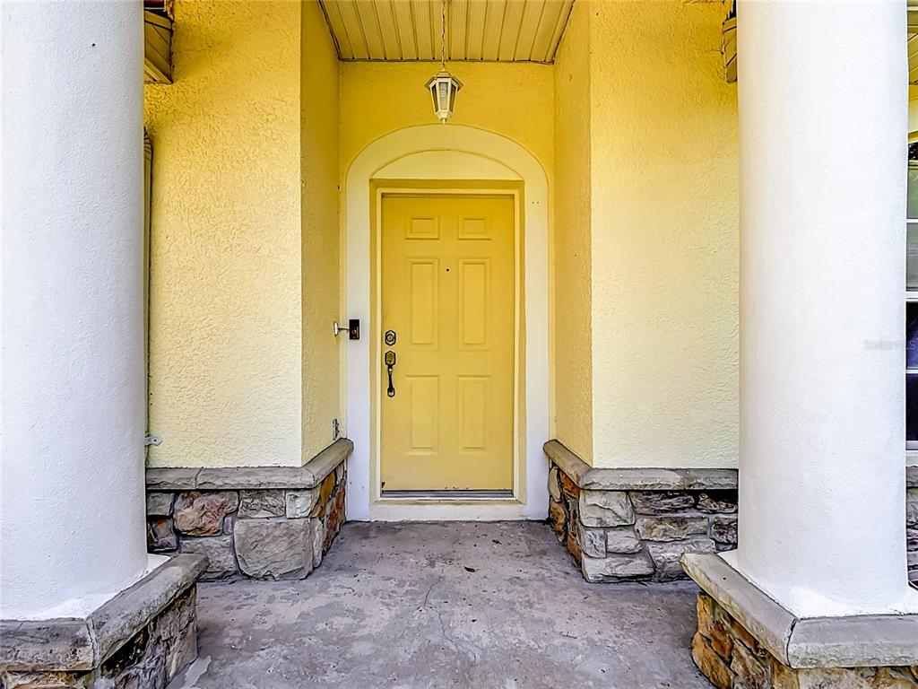 A yellow front door is framed by two white columns and stone base accents — 2917 EVANS WAY, KISSIMMEE, FL