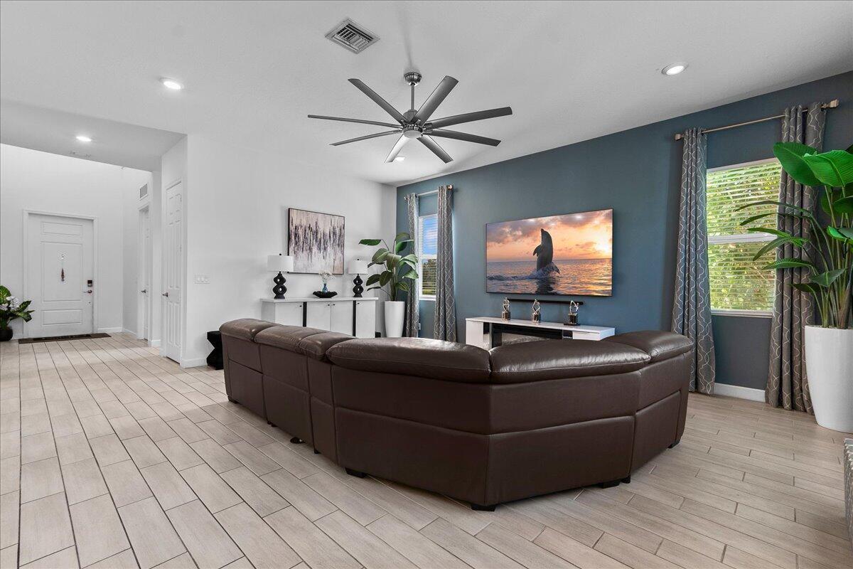A living room features a brown sectional sofa, a blue accent wall, and tile flooring — 19656 Tree Stand Terrace, Loxahatchee FL 33470, LOXAHATCHEE, FL