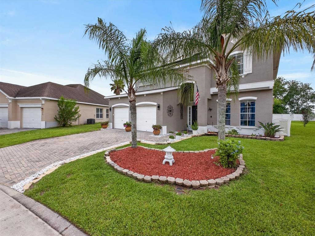 A two-story house with a paved driveway, palm trees, and a red-mulched garden bed — 2596 SAND HILL POINT CIRCLE, DAVENPORT, FL
