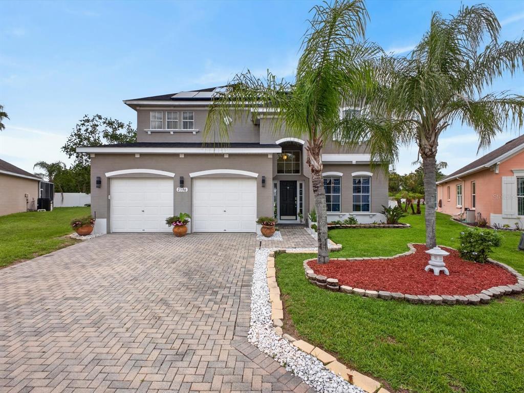 A two-story house with a gray stucco exterior, a paved driveway, and two garage doors — 2596 SAND HILL POINT CIRCLE, DAVENPORT, FL