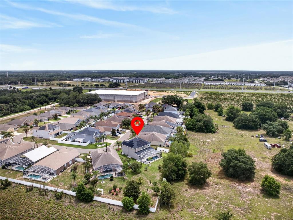 An aerial view shows a two-story house with solar panels and a pool enclosure — 2596 SAND HILL POINT CIRCLE, DAVENPORT, FL