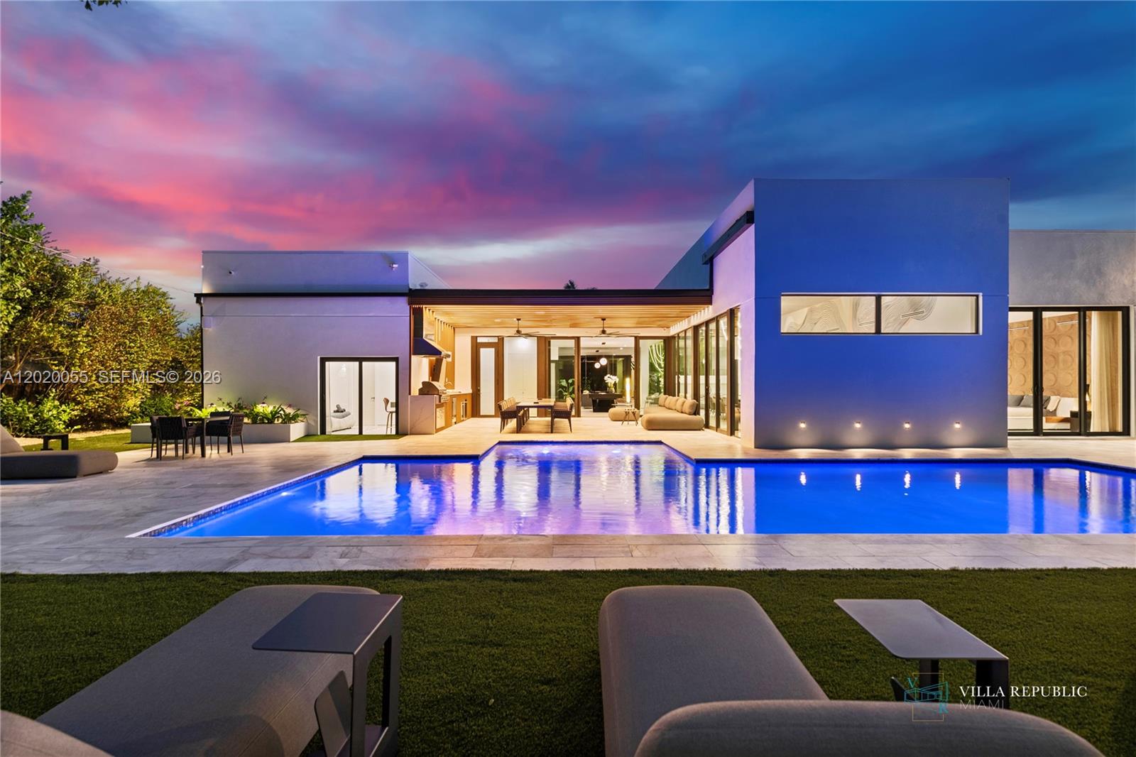 A modern house with a swimming pool and patio area at sunset — 1941 NE 196th Ter, Miami FL 33179, MIAMI, FL