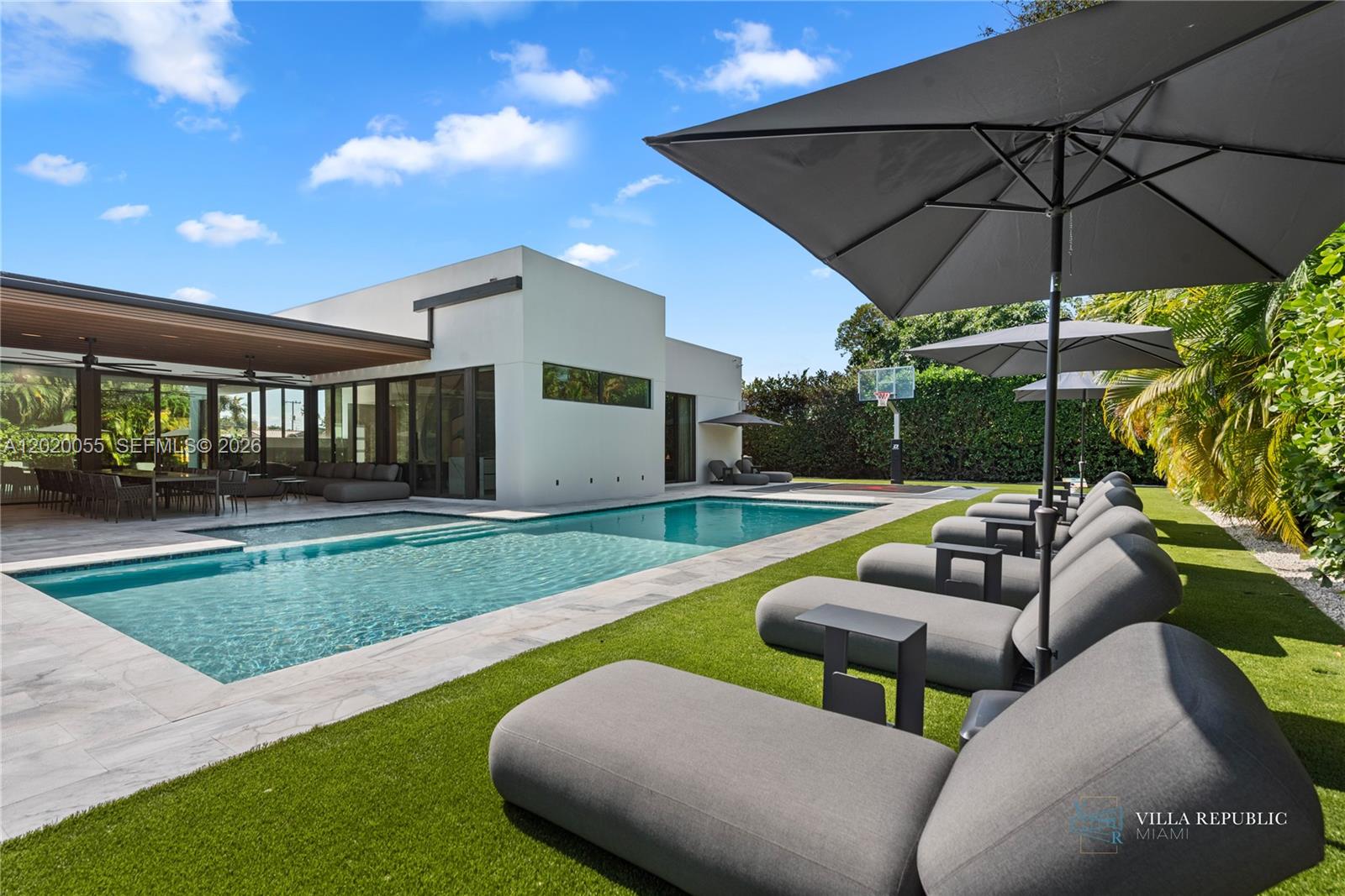 A modern house with a swimming pool, lounge chairs, and a basketball hoop in the yard — 1941 NE 196th Ter, Miami FL 33179, MIAMI, FL