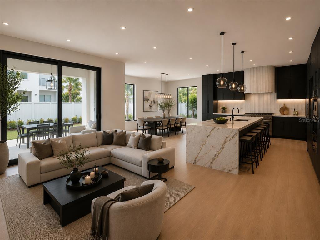An open-concept kitchen and living area features a stone island, dark cabinetry, and sliding doors — 1011 S MORRISON COURT, TAMPA, FL