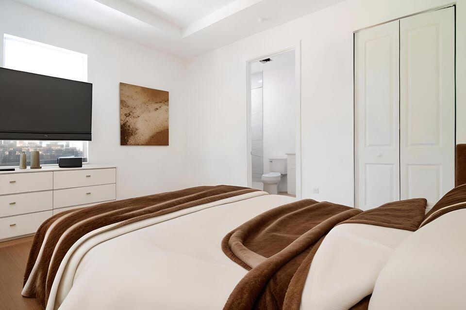 A bedroom with a white dresser, a brown-accented bed, and a doorway to a bathroom — 260 Rotonda Boulevard # 2, FL 33947, FL