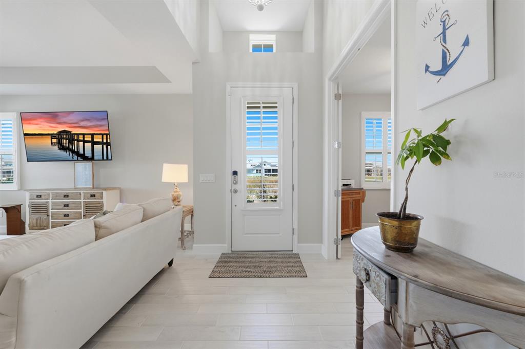 A bright entryway features white tile floors, a white front door, and a console table — 896 CORAL REEF WAY, DAYTONA BEACH, FL