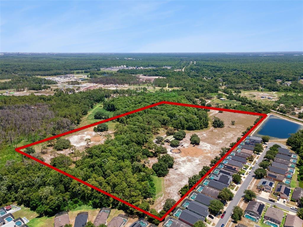 An aerial view shows a large, rectangular plot of land outlined in red near residential houses — BLUE JAY WAY, DAVENPORT, FL
