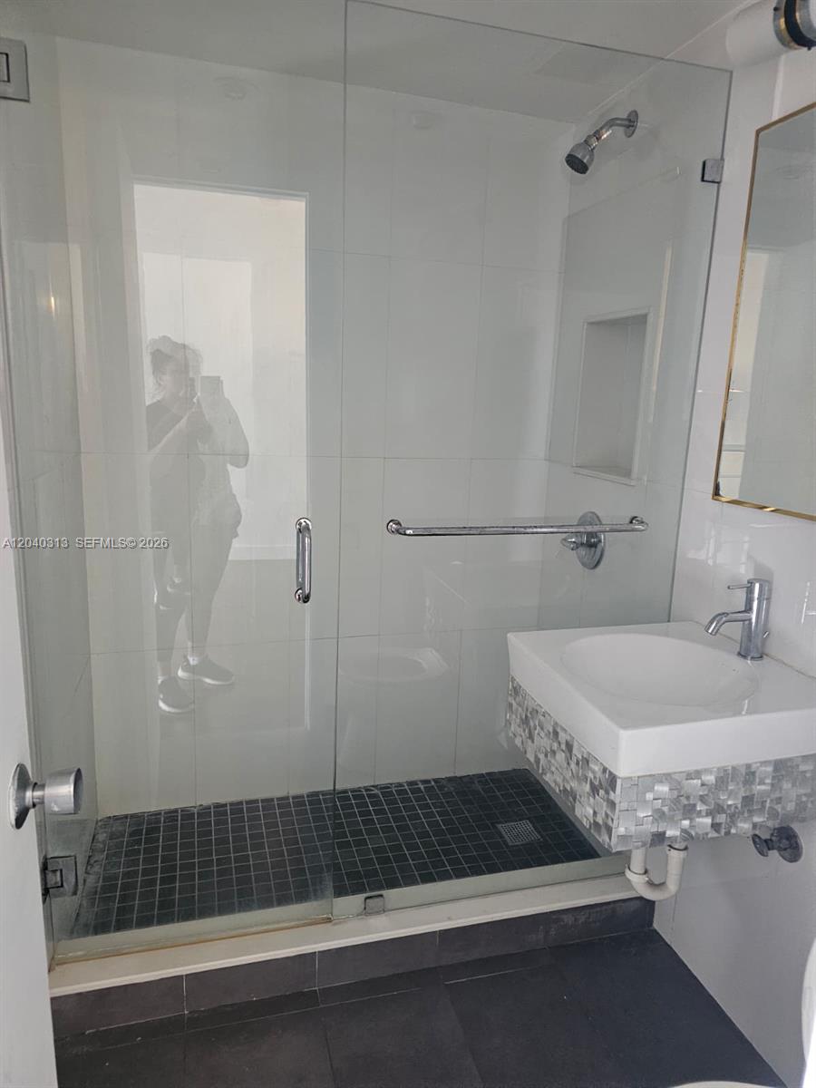 A bathroom features a glass-enclosed shower with a wall-mounted grab bar and a floating sink — 1614 Jefferson Ave # 3, Miami Beach FL 33139, MIAMI BEACH, FL