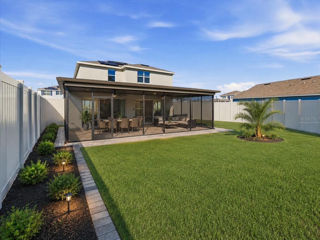 A backyard features a screened-in patio, a manicured lawn, and a white privacy fence — 1211 TAHITIAN SUNRISE DRIVE, PLANT CITY, FL