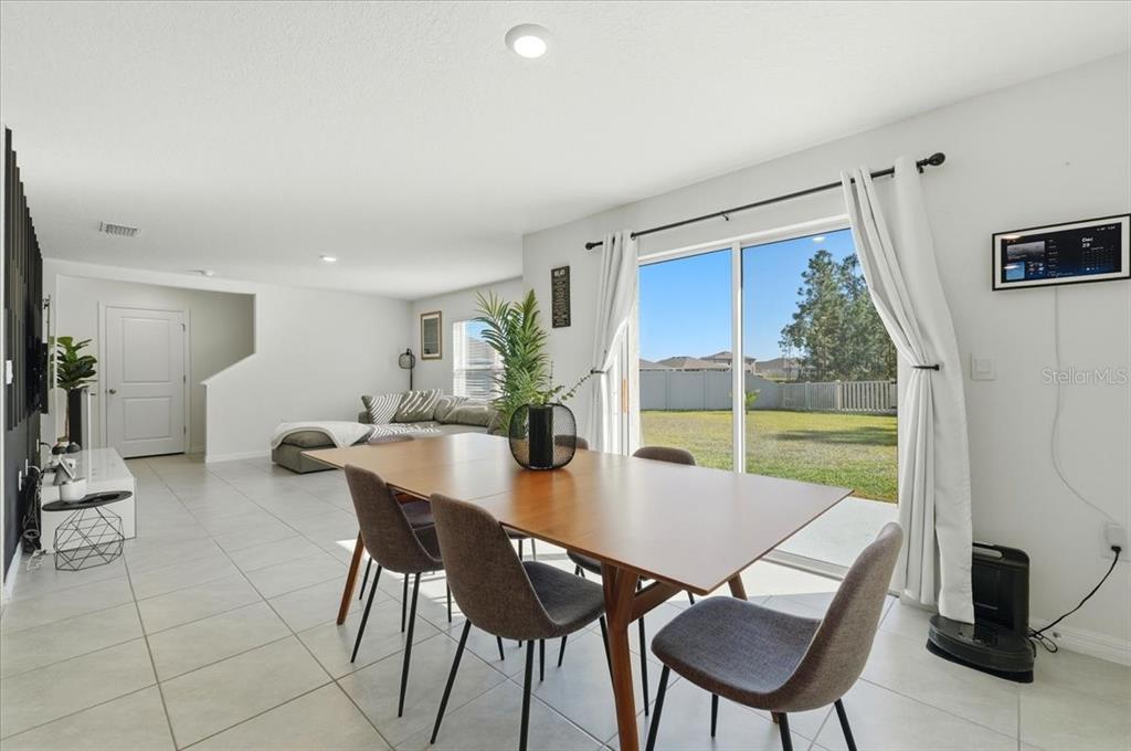 A dining area with a wooden table and chairs opens to a backyard through sliding doors — 1211 TAHITIAN SUNRISE DRIVE, PLANT CITY, FL