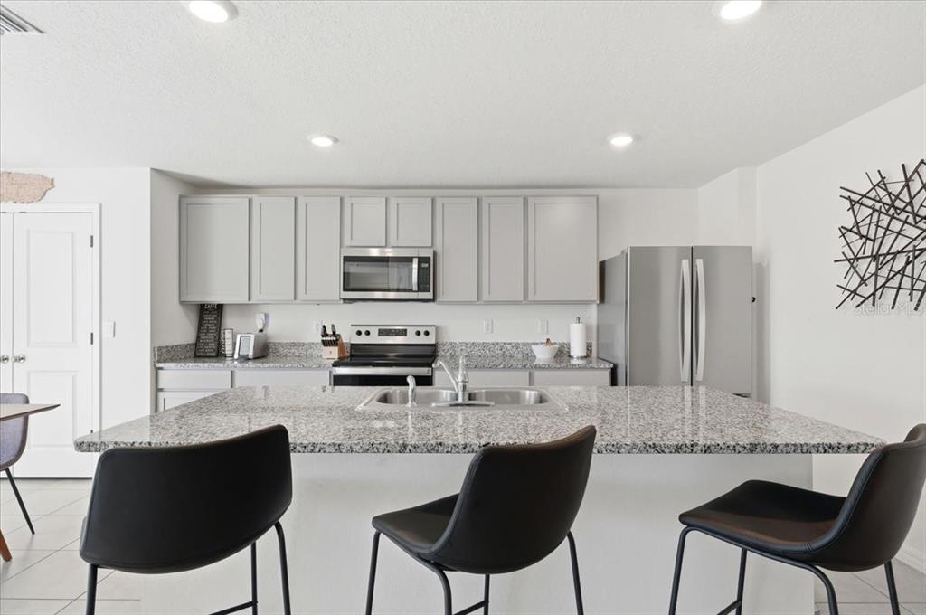 A kitchen features gray cabinets, granite countertops, stainless steel appliances, and a central island — 1211 TAHITIAN SUNRISE DRIVE, PLANT CITY, FL