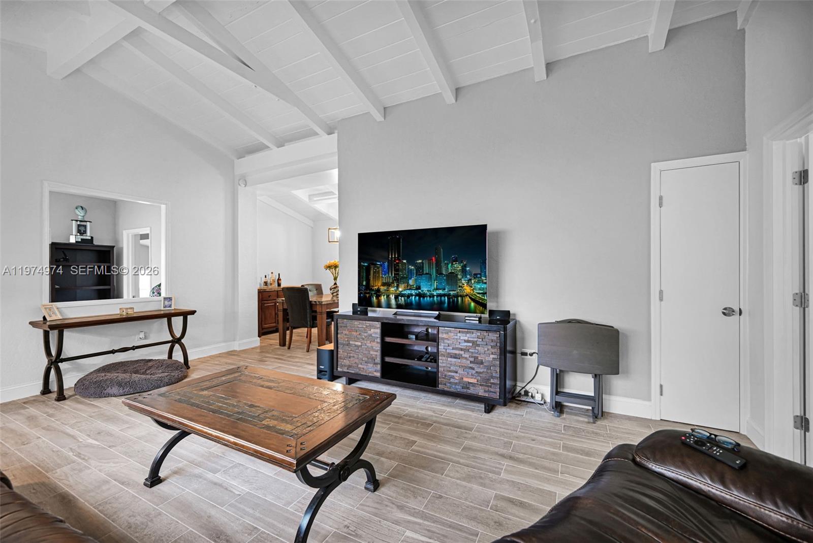 A living room features a vaulted ceiling, tile flooring, a stone-accented media console, and furniture — 1021 NE 82nd Ter, Miami FL 33138, MIAMI, FL