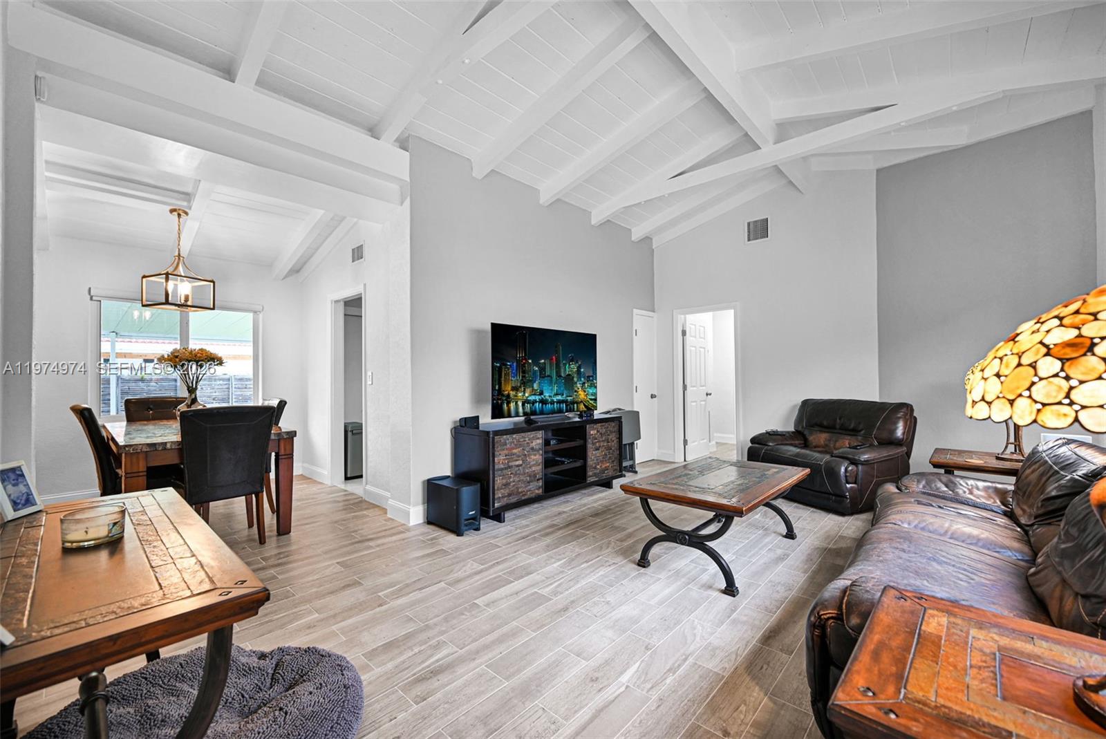 A living room and dining area feature vaulted ceilings, tile flooring, and leather furniture — 1021 NE 82nd Ter, Miami FL 33138, MIAMI, FL