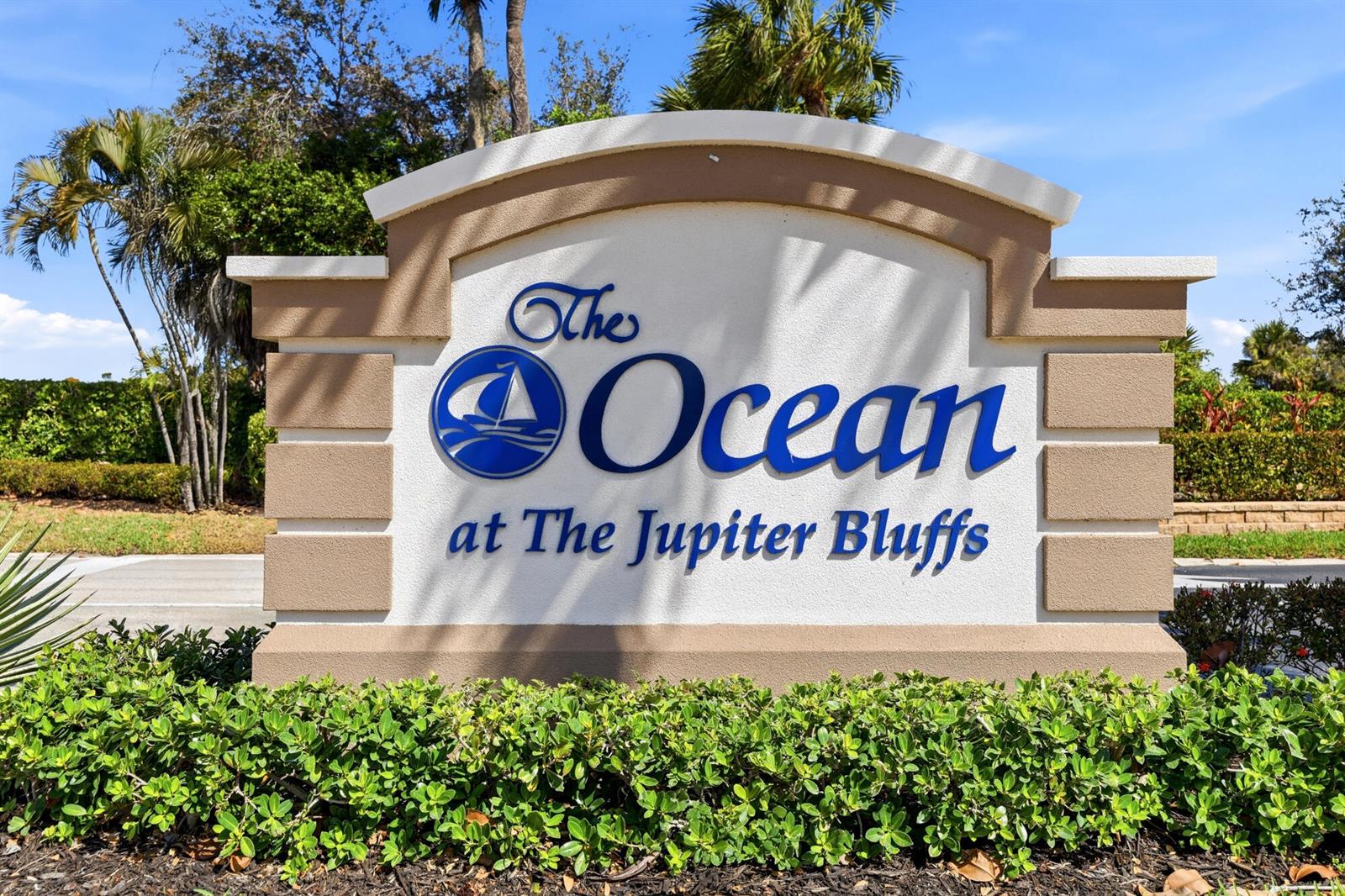 A beige monument sign for The Ocean at The Jupiter Bluffs stands outdoors with landscaping — 401 Ocean Bluffs Boulevard # 104, Jupiter FL 33477, JUPITER, FL