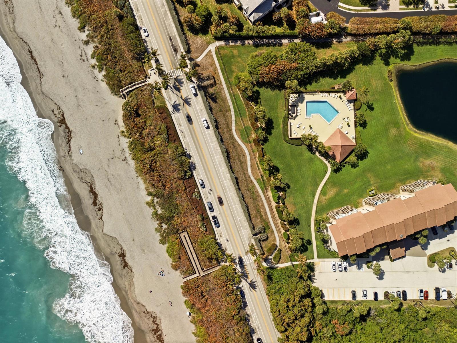 Aerial view of a coastal road, beach, swimming pool, and a multi-story building — 401 Ocean Bluffs Boulevard # 104, Jupiter FL 33477, JUPITER, FL