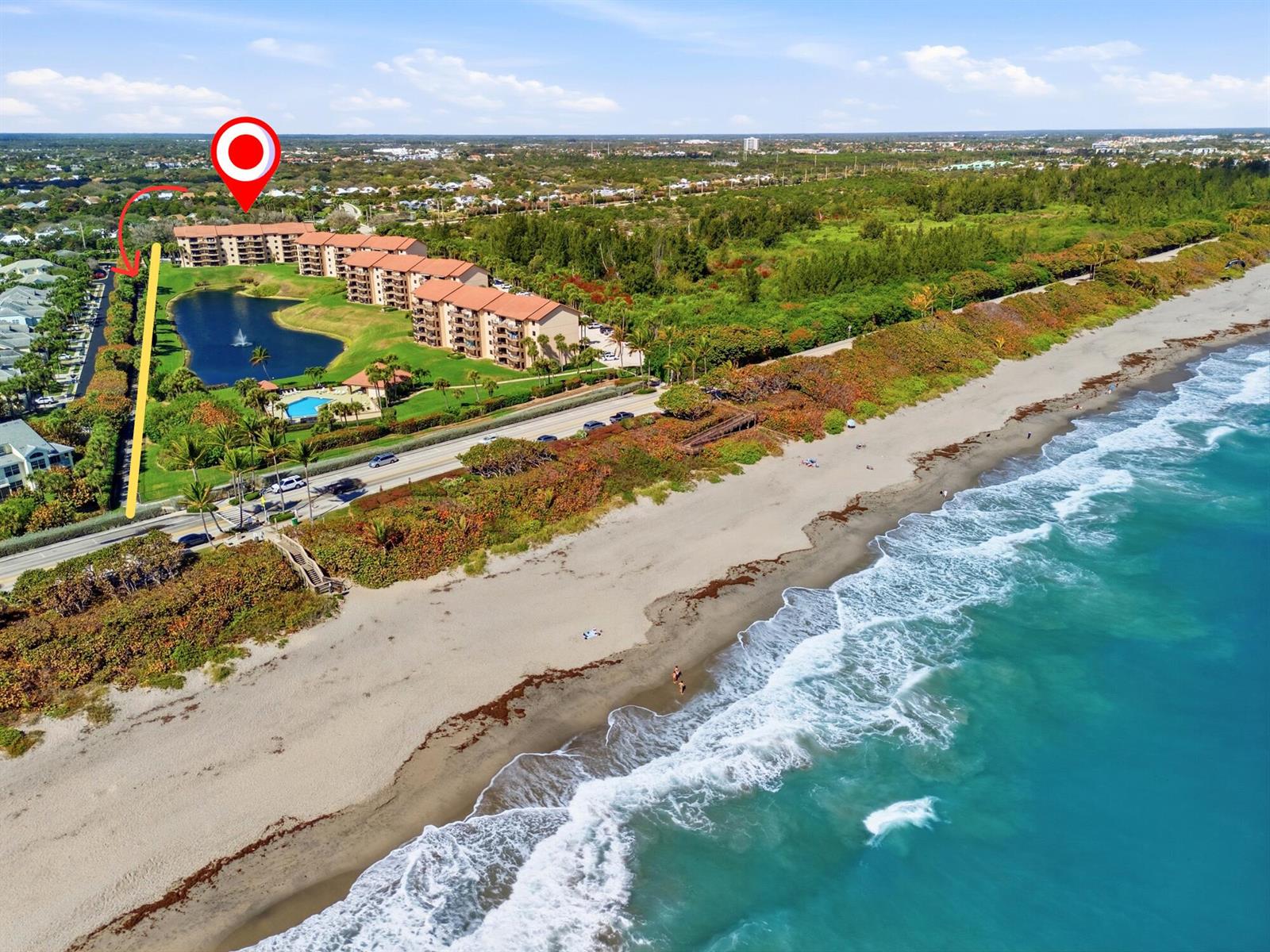 An aerial view shows a multi-story apartment complex situated next to a beach and ocean — 401 Ocean Bluffs Boulevard # 104, Jupiter FL 33477, JUPITER, FL