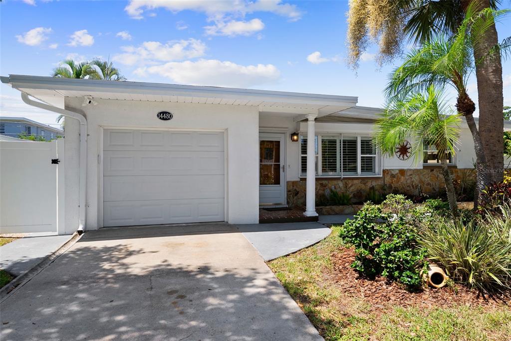 A white single-story house features a one-car garage, a stone facade, and a palm tree — 14480 120TH AVENUE, LARGO, FL