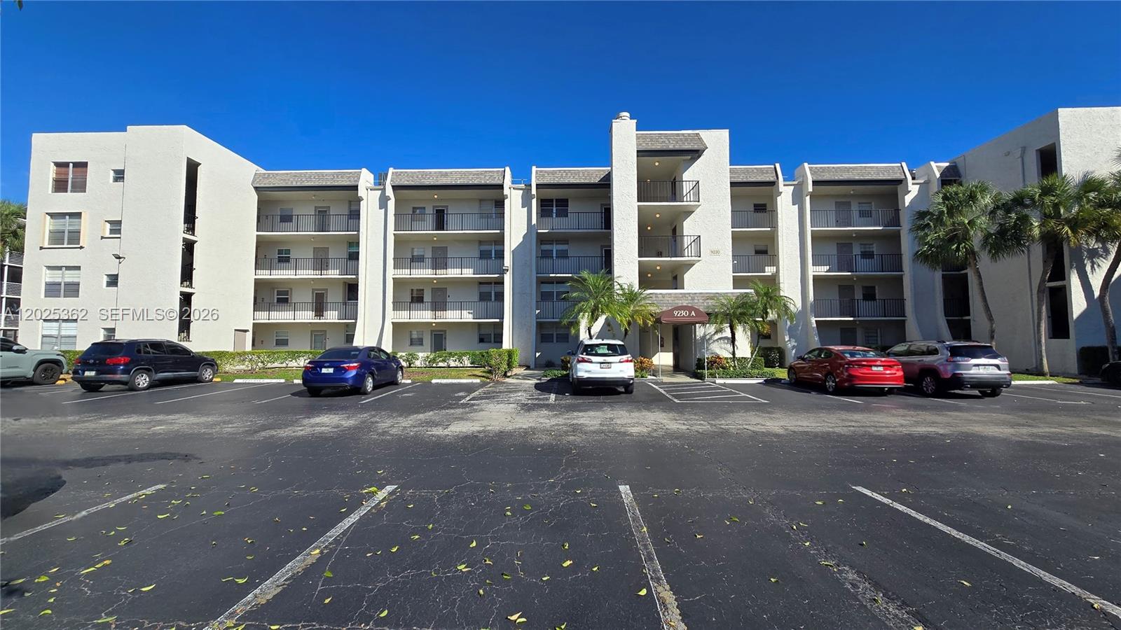 A multi-story apartment building features balconies and a parking lot with several parked cars — 9230 Lagoon Pl # 310, Davie FL 33324, DAVIE, FL