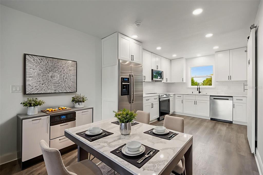 A kitchen and dining area with white cabinets, stainless steel appliances, and a marble-topped table — 5317 CURRY FORD ROAD 203 - BLDG L, ORLANDO, FL