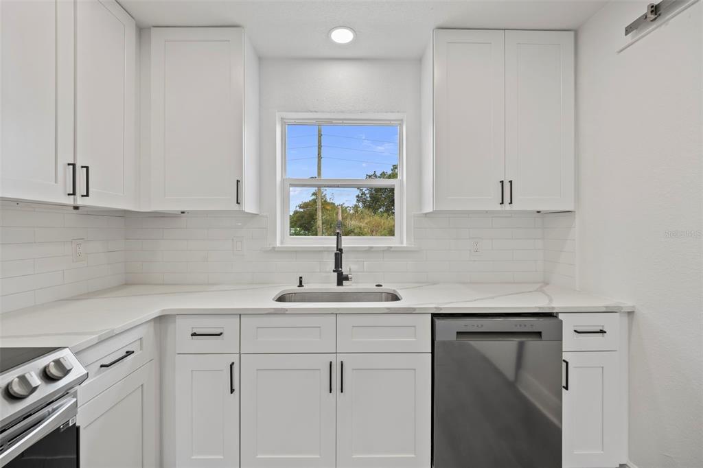 A kitchen features white shaker cabinets, a stainless steel dishwasher, and a white quartz countertop — 5317 CURRY FORD ROAD 203 - BLDG L, ORLANDO, FL
