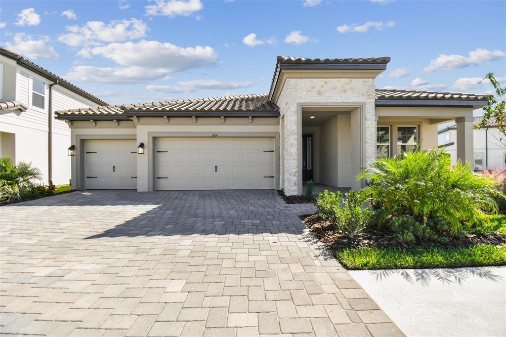 A single-story house features a stone-accented entryway, a paver driveway, and a three-car garage — 1664 DRUMMOND POINT, ZEPHYRHILLS, FL