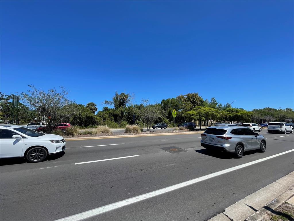 A view of a multi-lane road with several cars driving past a wooded area — 1519 MANATEE AVENUE E, BRADENTON, FL