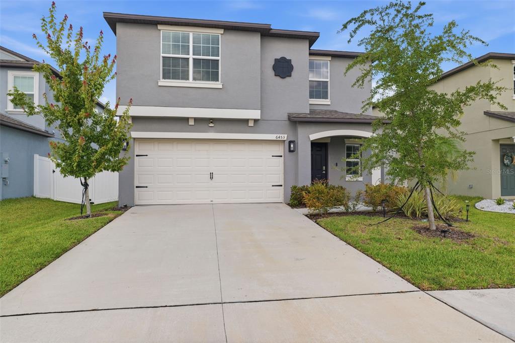 A two-story gray house features a two-car garage, a front entrance, and a concrete driveway — 6453 BACK FORTY LOOP, ZEPHYRHILLS, FL