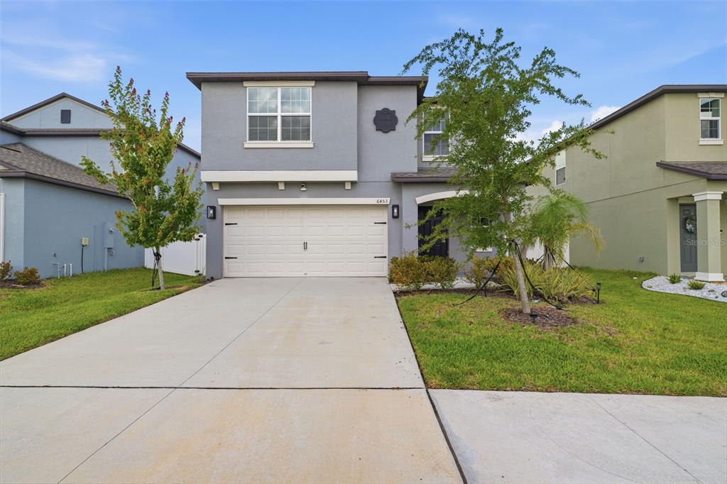 A two-story gray house with a two-car garage and a front lawn — 6453 BACK FORTY LOOP, ZEPHYRHILLS, FL