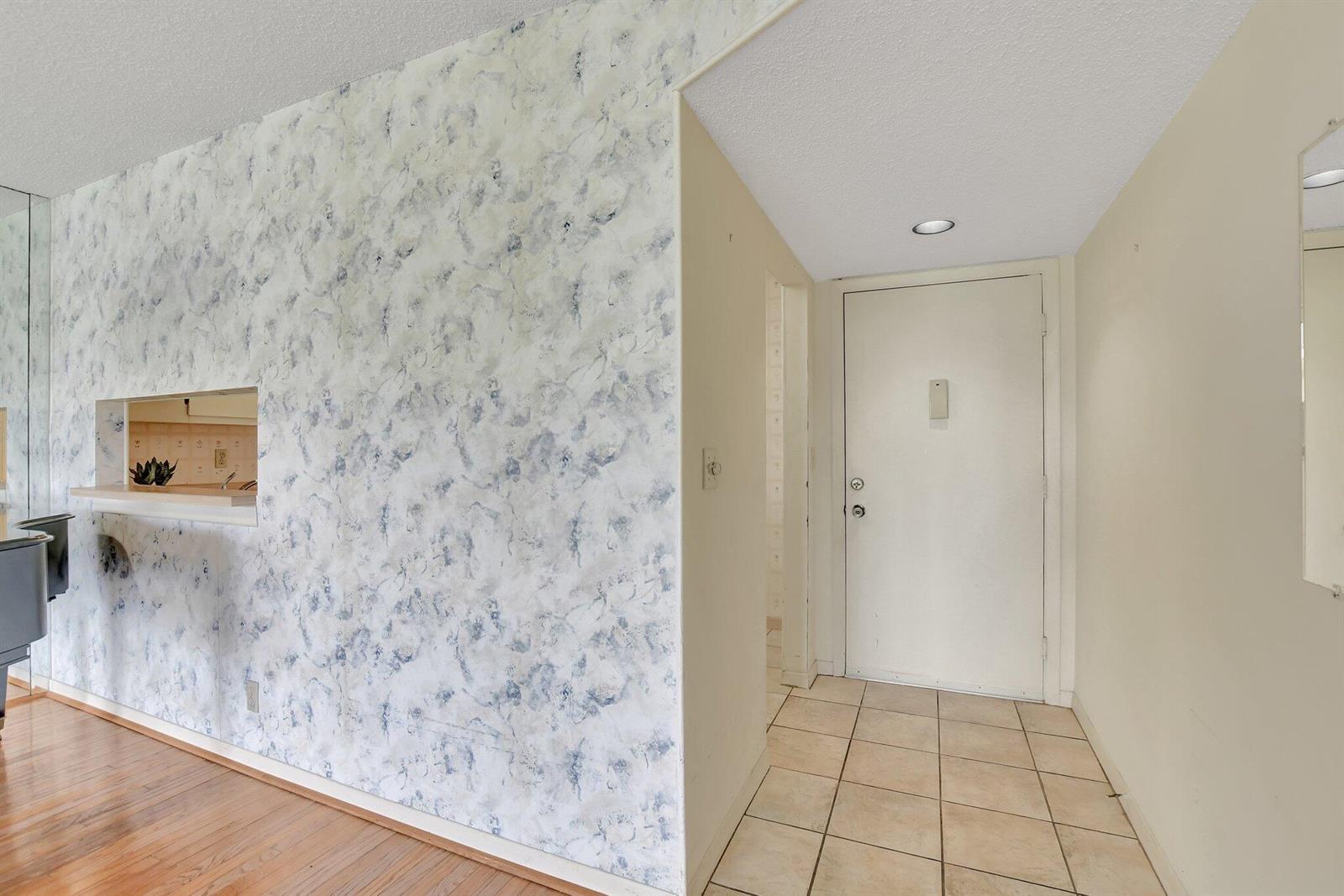An entryway features a tiled floor, a white door, and a wall with blue-patterned wallpaper — 5340 Las Verdes Circle # 208, Delray Beach FL 33484, DELRAY BEACH, FL