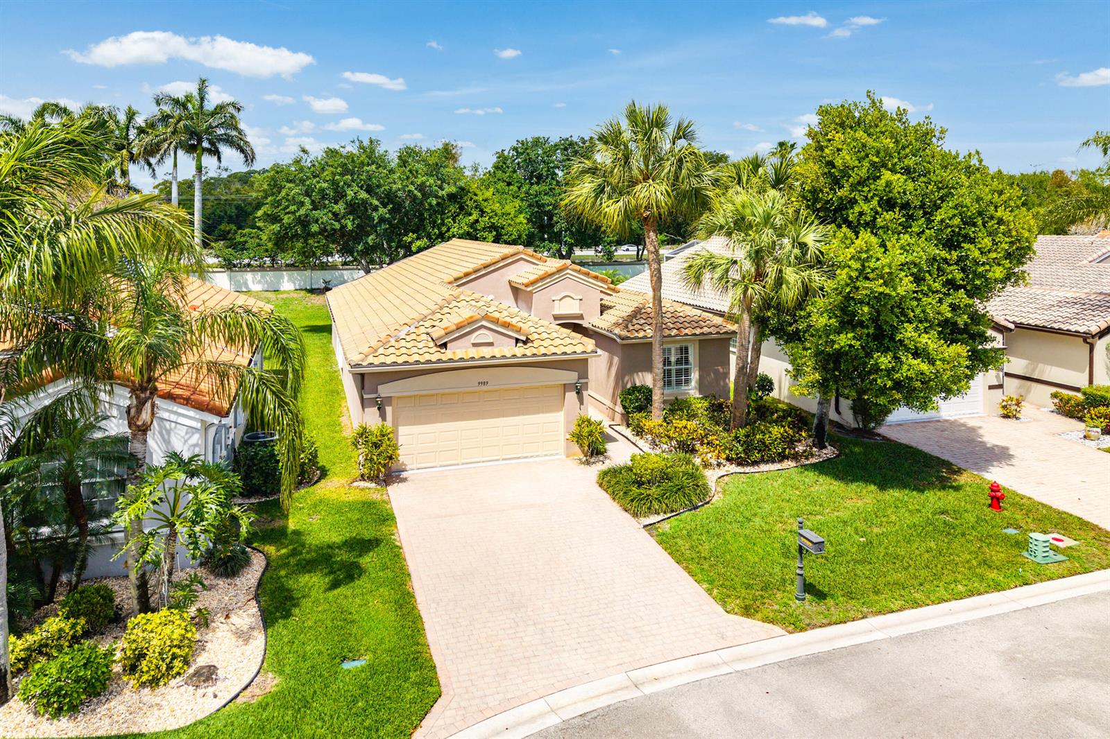 An aerial view shows a single-story house with a tan tile roof and paved driveway — 9989 Torino Drive, Lake Worth FL 33467, LAKE WORTH, FL