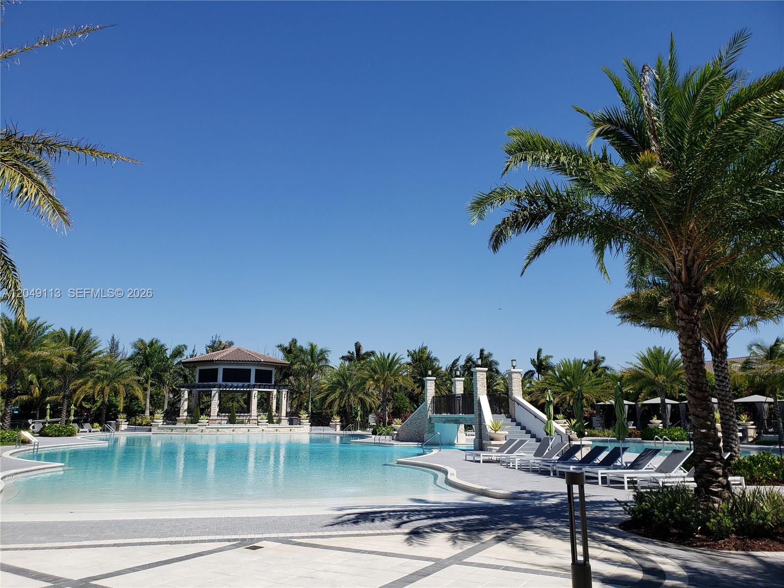 A large outdoor swimming pool features a stone gazebo, a bridge, and surrounding palm trees — 10620 NW 88th St # 223, Doral FL 33178, DORAL, FL