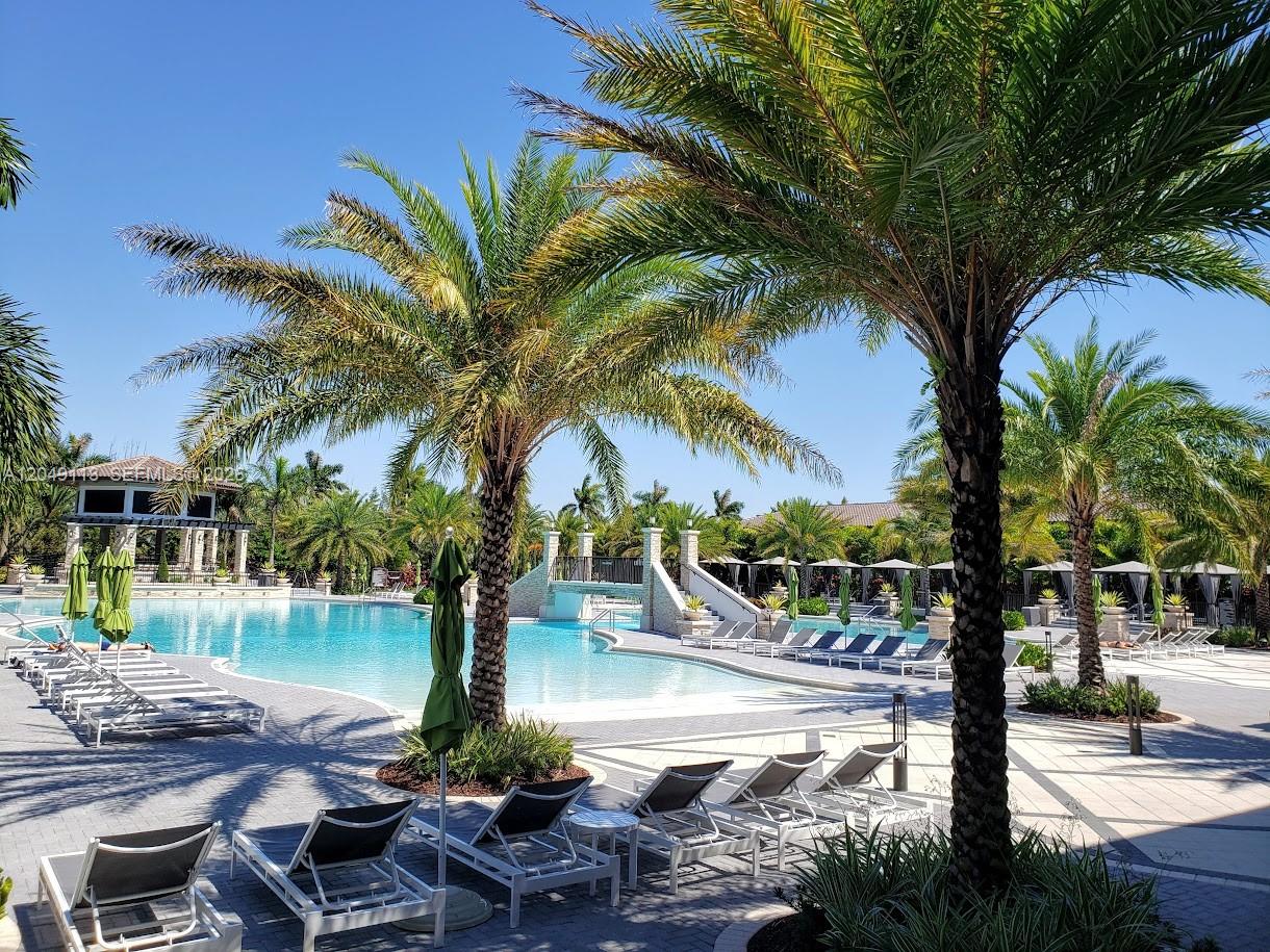 A swimming pool area features lounge chairs, palm trees, and a small bridge — 10620 NW 88th St # 223, Doral FL 33178, DORAL, FL