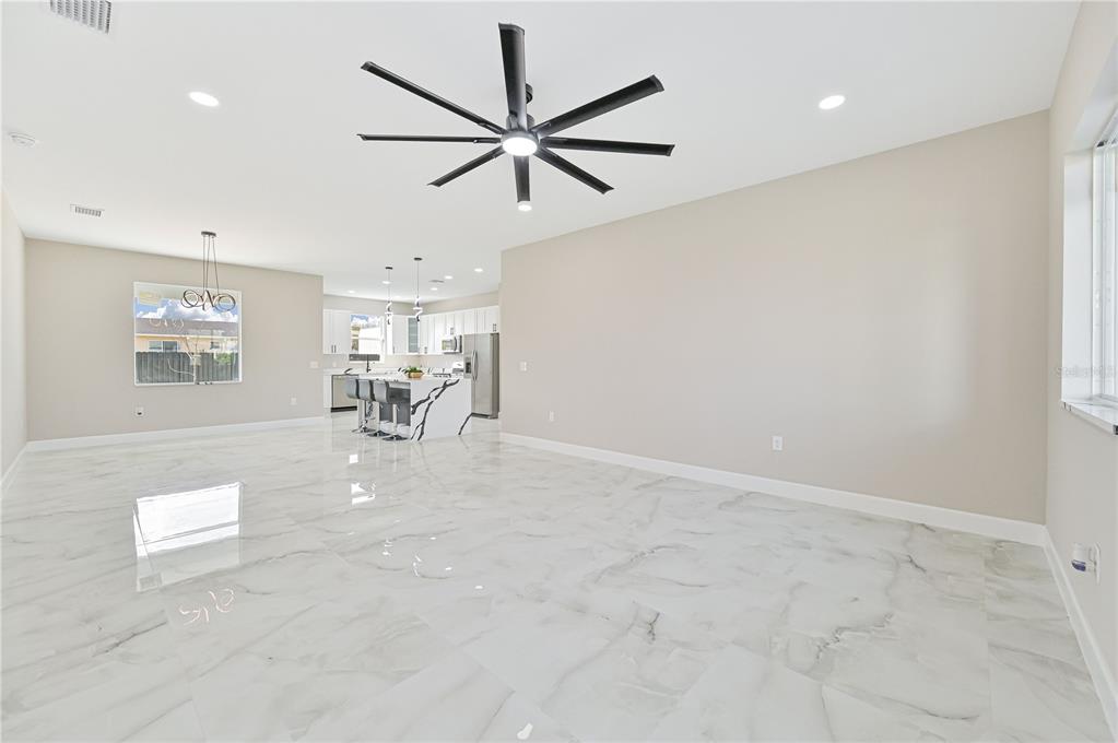 An open-concept living and dining area features white marble floors, a black ceiling fan, and furniture — 1326 NE 7TH PLACE, CAPE CORAL, FL