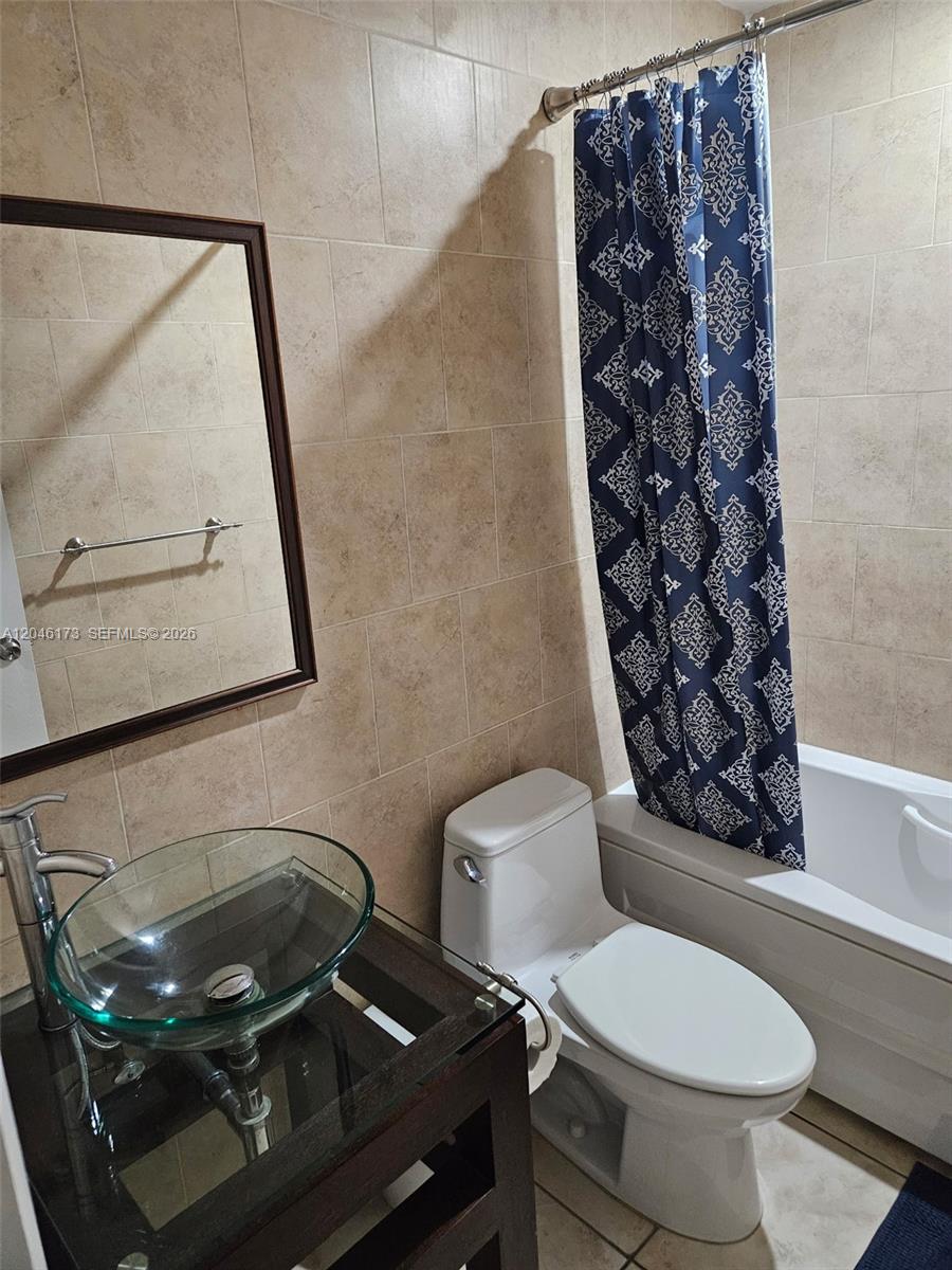 A bathroom features a glass vessel sink, a white toilet, and a patterned shower curtain — 9483 SW 76th St # N8, Miami FL 33173, MIAMI, FL
