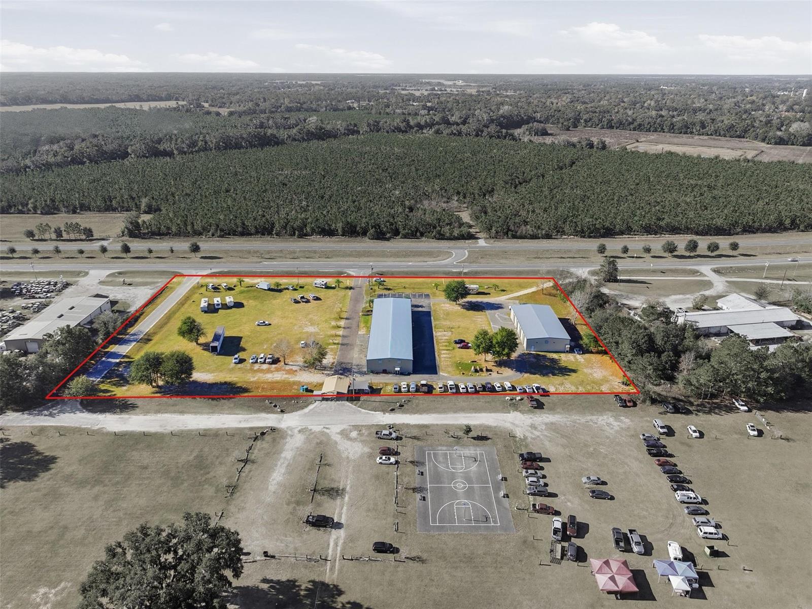 An aerial view shows two large metal buildings on a grassy lot with parking — 20761 US Highway 27, Williston FL 32696, WILLISTON, FL