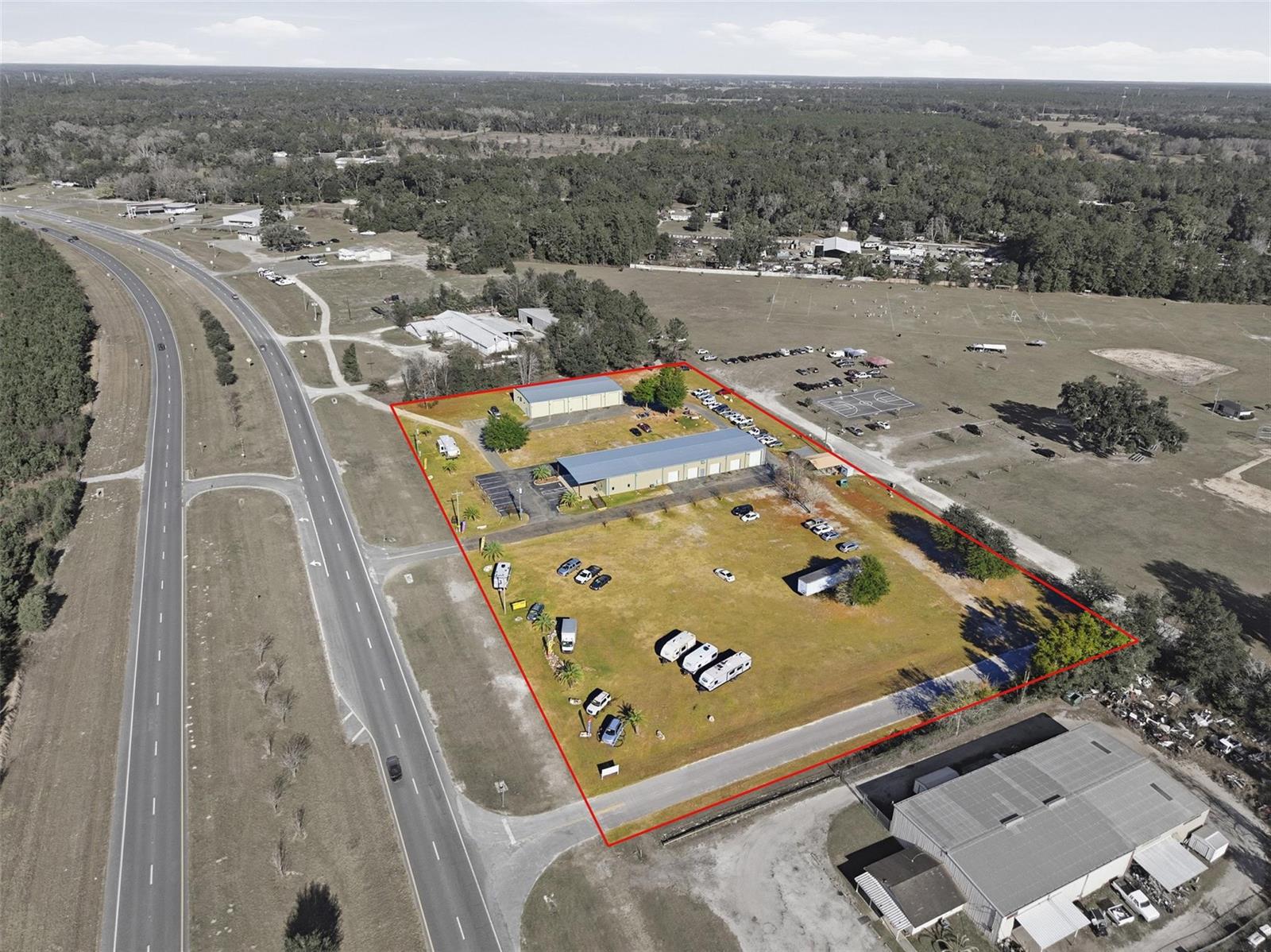 An aerial view shows a commercial property outlined in red, featuring two buildings and parking — 20761 US Highway 27, Williston FL 32696, WILLISTON, FL