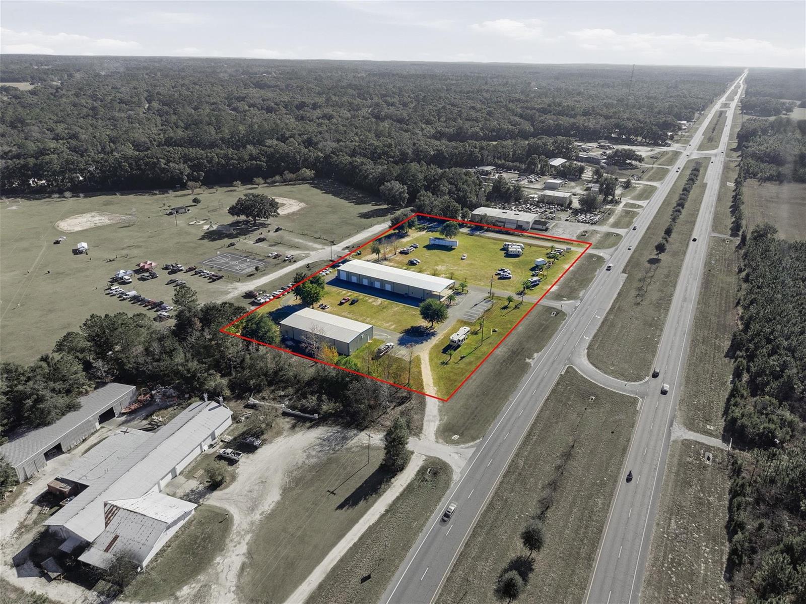 An aerial view shows two commercial buildings on a large lot beside a highway — 20761 US Highway 27, Williston FL 32696, WILLISTON, FL