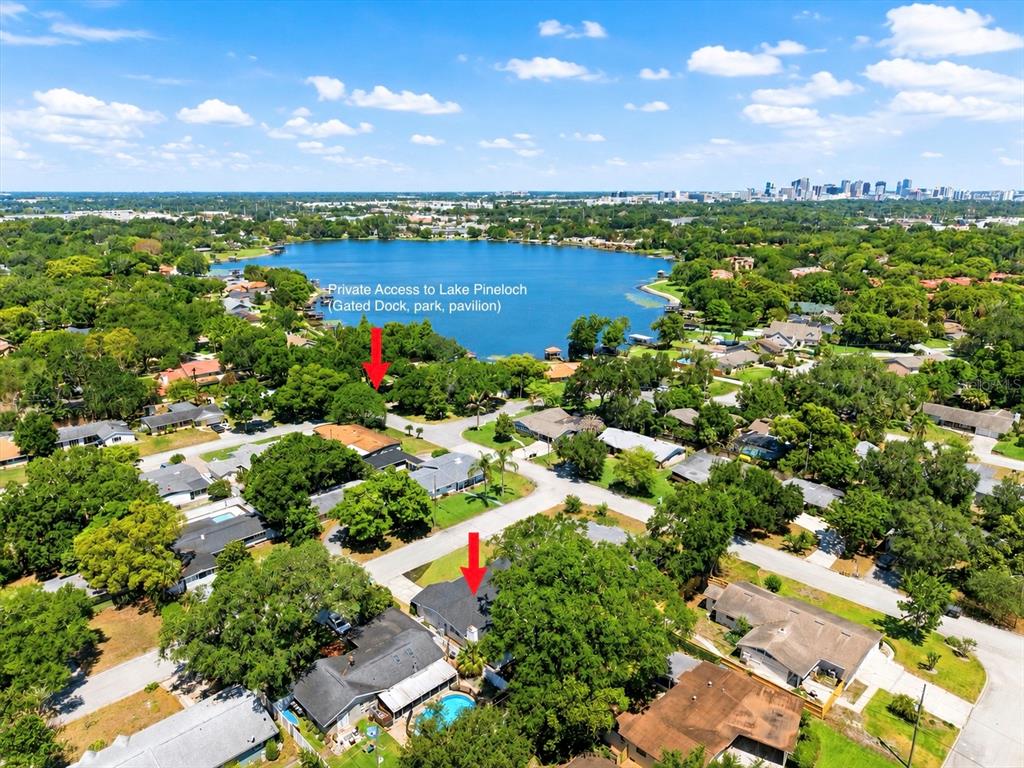 An aerial view shows residential houses, dense trees, and a lake with a private dock — 3256 WICKERSHAM COURT, ORLANDO, FL