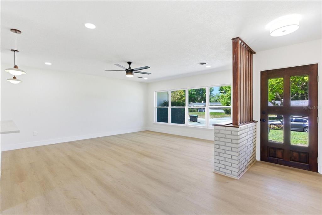 An open living area features light wood-look flooring, a ceiling fan, and a brick partition — 3256 WICKERSHAM COURT, ORLANDO, FL