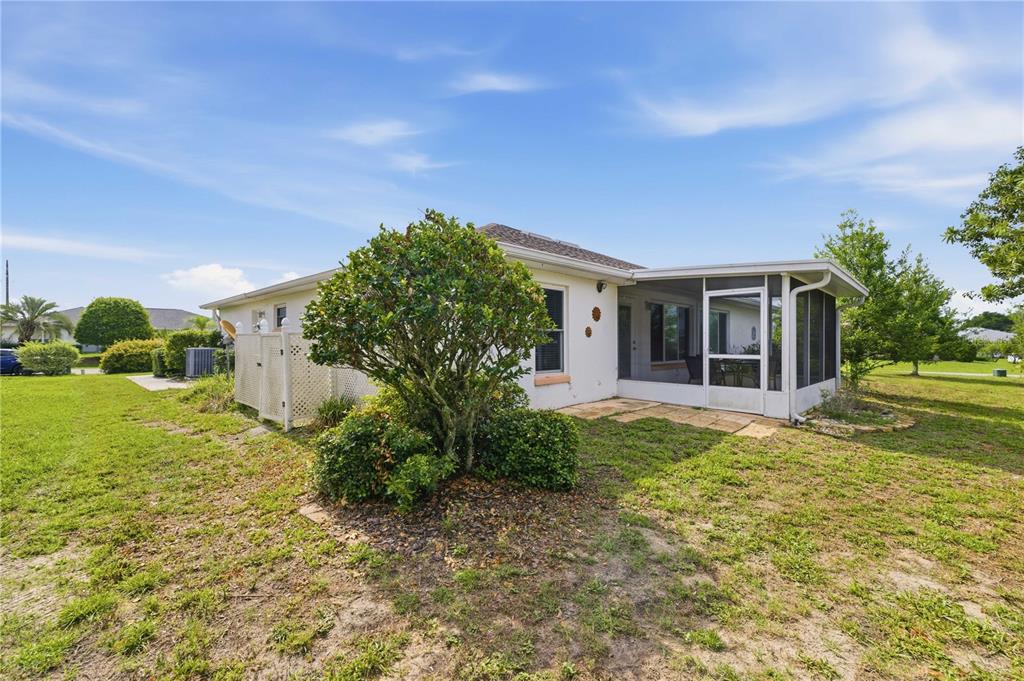 The exterior of a single-story house features a screened-in porch and a small privacy fence — 8490 SW 60TH COURT, OCALA, FL