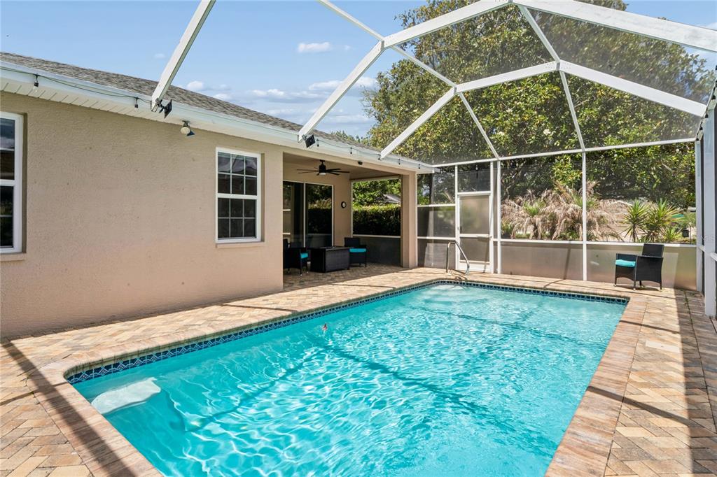 A rectangular swimming pool sits on a paved patio enclosed by a white screen cage — 4354 BURNBERRY GLEN CT, SPRING HILL, FL
