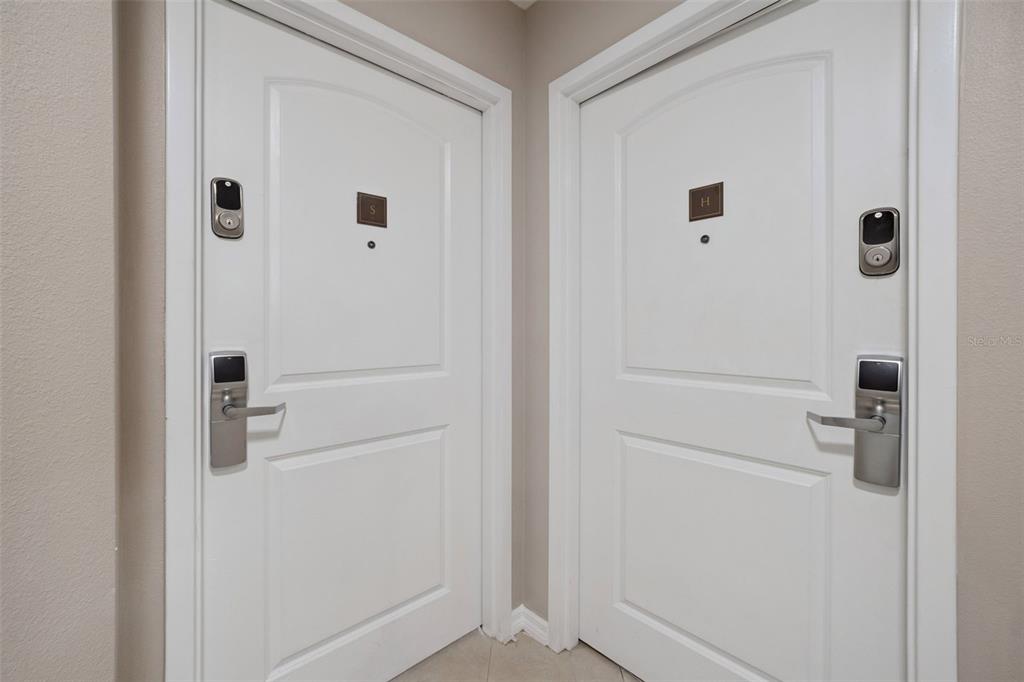 Two white doors with electronic locks and lettered plaques are positioned in a corner — 7395 UNIVERSAL BOULEVARD UNIT 1205, ORLANDO, FL