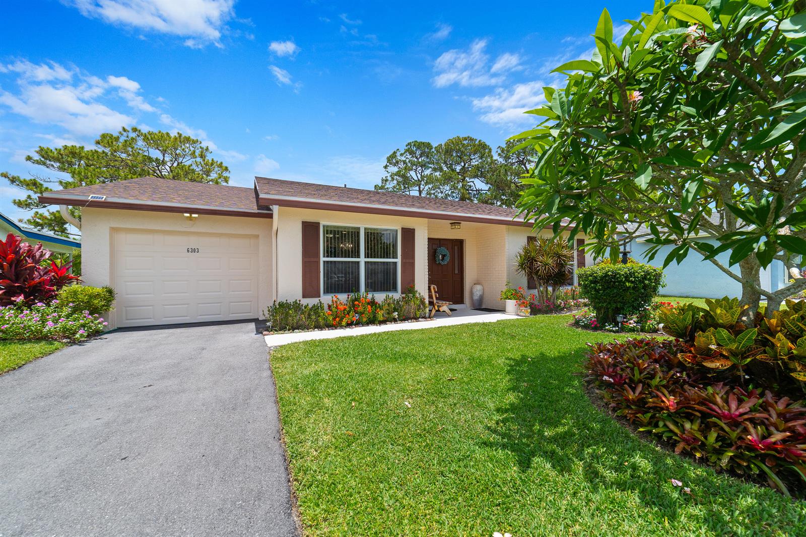 A single-story house with a beige exterior, brown shutters, a garage, and a landscaped yard — 6303 Silver Moon Lane, FL 33463, FL