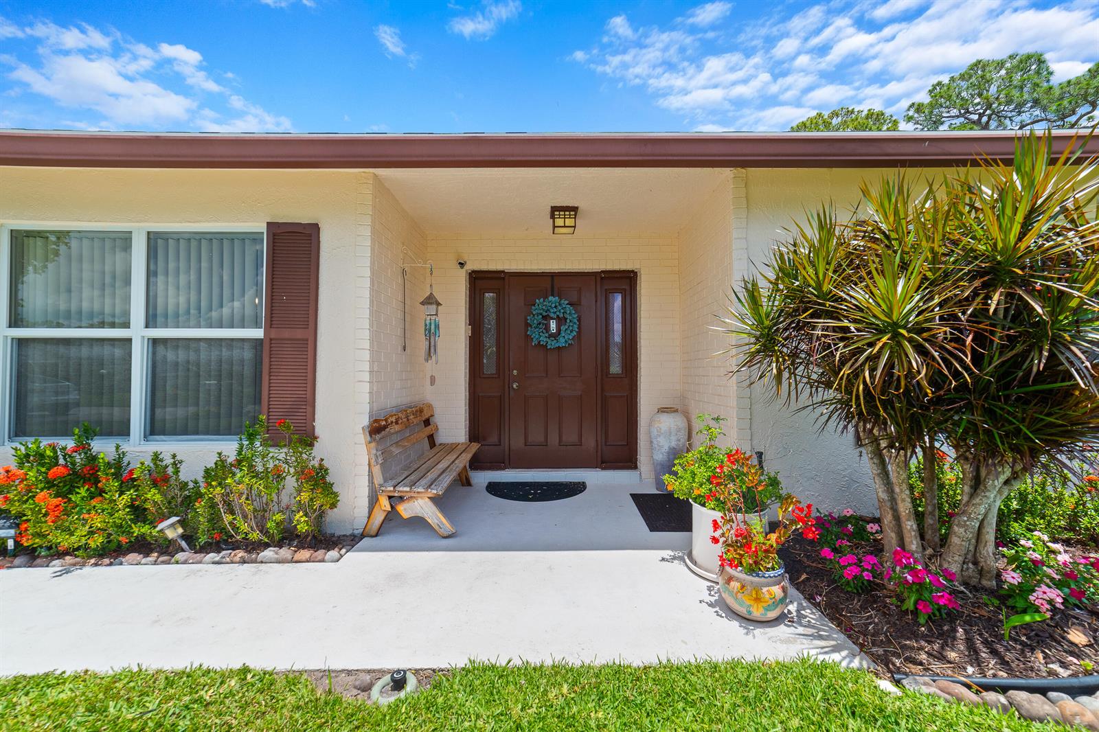 The exterior of a house features a concrete porch, a brown front door, and landscaping — 6303 Silver Moon Lane, FL 33463, FL