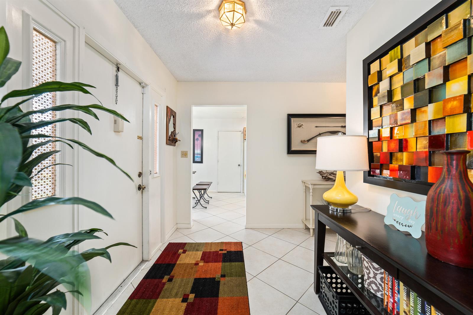 An entryway features white tile floors, a colorful rug, a console table, and wall art — 6303 Silver Moon Lane, FL 33463, FL